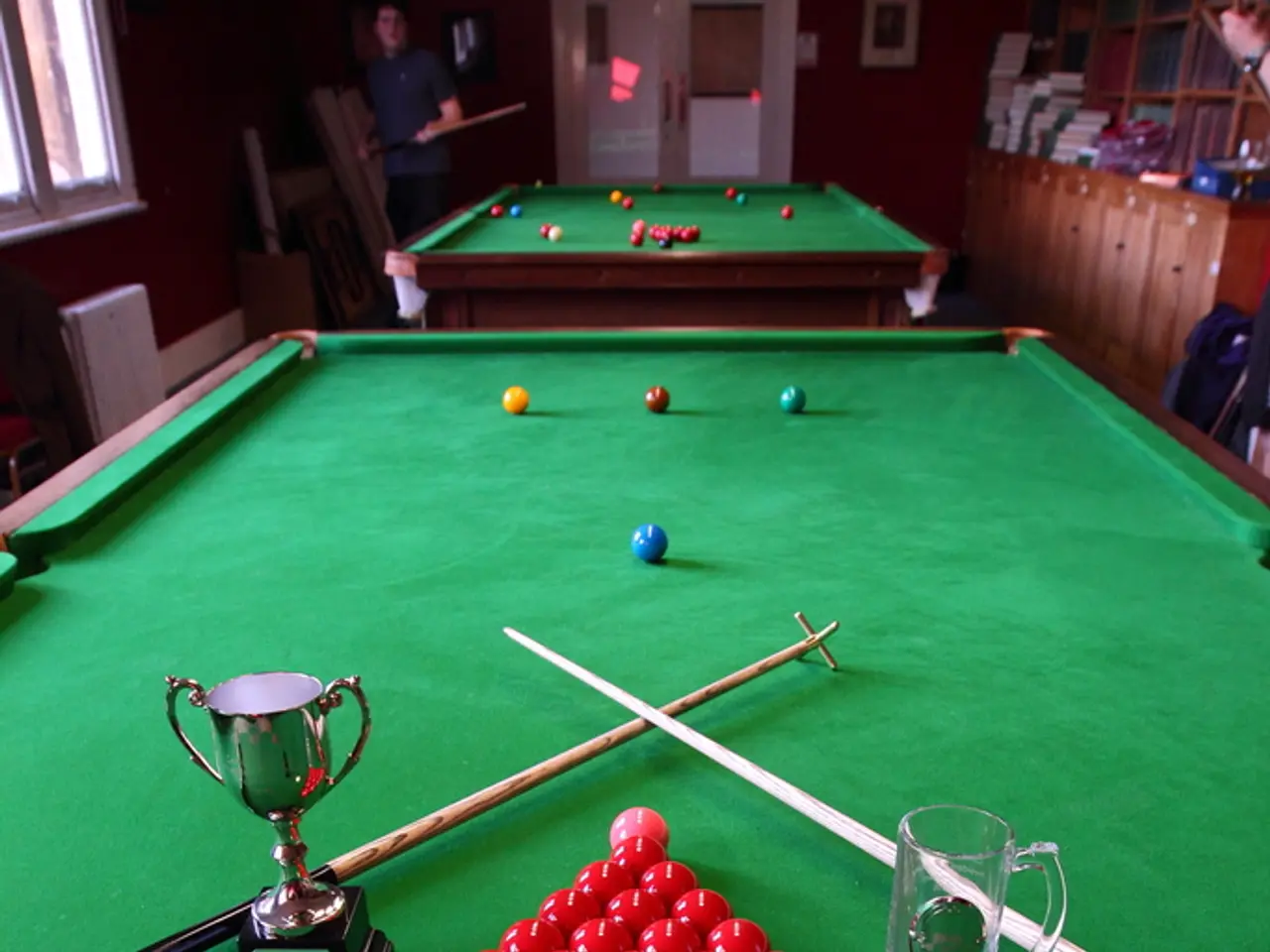 A trophy,a glass mug and some balls are placed on a billiards table.