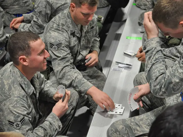 In this image there are people sitting on benches and playing cards.