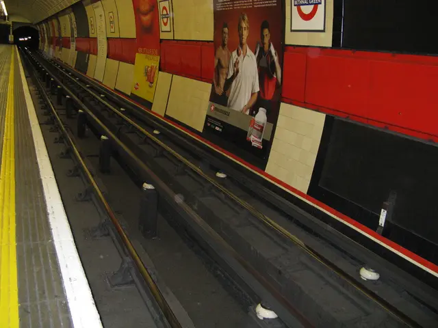 Here we can see a train track. Posters are on the wall.