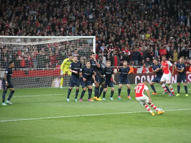 In the image there are football players in the ground and behind the ground there is a huge crowd.